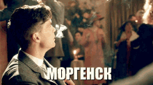 a man in a suit and tie is smoking a cigarette and the word morgenck is on the bottom