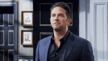 a man in a suit and black shirt stands in front of a black door