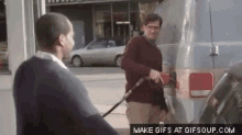 a man is pumping gas into another man 's van .