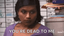 a woman is standing in front of a pile of papers and says `` you 're dead to me ''
