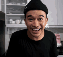a man wearing a black beanie and a black shirt smiles