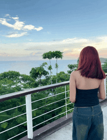 a woman with red hair stands on a balcony overlooking a body of water