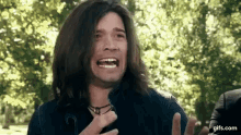 a man with long hair is making a funny face .