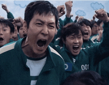 a group of people are screaming and one of them has the number 001 on his jacket