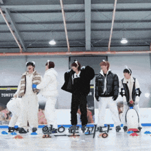 a group of people standing on a ice rink with a sign that says tomoya in the background
