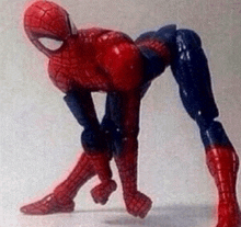 a spider man action figure is kneeling down on a table .