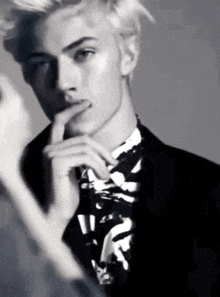 a black and white photo of a man in a suit and tie with his hand on his chin .