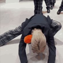 a man in a suit is kneeling down on the floor with his head on a pillow .