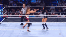 two women are wrestling in a ring with a referee and a crowd watching