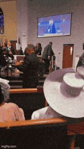 a woman in a purple hat sits in front of a large screen
