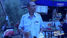 a man in a blue shirt is holding a magazine in front of an astro citra sign