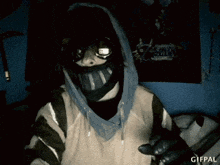 a person wearing a mask and a hoodie is sitting in front of a poster of zelda .