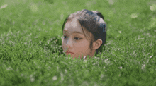 a girl is laying in the grass with her head sticking out of it