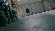 a man in a gas mask stands in a warehouse