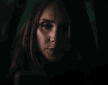 a close up of a woman 's face in the dark with a green background