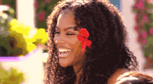 a woman with curly hair has a flower in her hair and is smiling