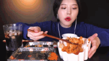 a woman in a blue sweater is eating a bowl of food