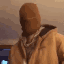 a man wearing a beanie and a jacket is standing in front of a window .