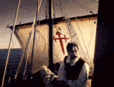 a man stands on a boat with a cross on it