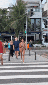 a woman in a bikini walks across a crosswalk in front of a building that says belmonte