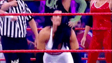 a woman is sitting in a wrestling ring with a referee and a hulk behind her .