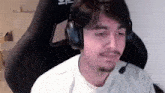 a man is wearing headphones and a microphone while sitting in a gaming chair .