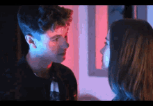 a man and a woman are looking into each other 's eyes in a dark room .
