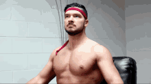 a shirtless man wearing a red headband looks up