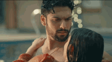 a man with a beard is holding a woman in a pool