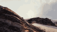 a black tank is driving down a dirt hill