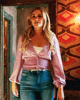 a woman in a purple top and jeans is standing in front of a colorful wall