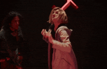 a woman holding a slingshot with a red light behind her