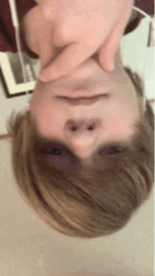 a person 's head is upside down with their hands on their face