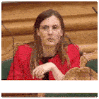a woman in a red jacket is sitting in front of a microphone and making a funny face .