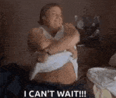 a woman is sitting on a bed with her arms around her stomach and taking off her shirt .