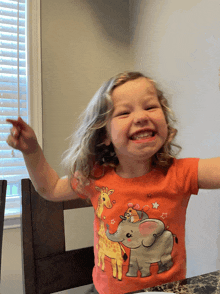 a little girl wearing a red shirt with a giraffe and elephant on it