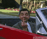 a man is giving the middle finger while sitting in a red car