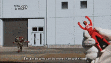 a man is holding a red figure in front of a building and says i 'm a man who can do more than just shoot