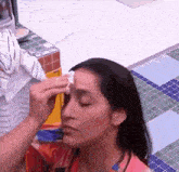 a woman is cleaning her face with a towel in a kitchen .