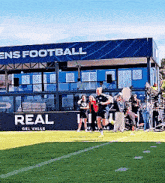 a group of people running on a field in front of a building that says ' ens football '
