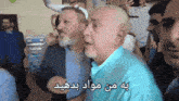 a man in a blue shirt is talking to another man in a crowd of people