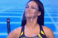 a woman wearing a face shield and glasses is standing in front of a microphone on a stage .