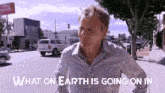 a man is walking down a street with the words what on earth is going on in