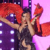 a drag queen in a black dress with red feathers