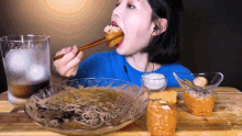 a woman is eating noodles with chopsticks and a glass of water