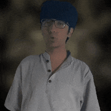 a man wearing glasses and a blue hat is making a surprised face