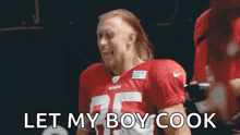 a football player in a red jersey is saying `` let my boy cook '' while standing on a field .