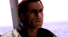 a man is sitting on a boat in the ocean looking out the window .