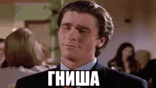 a man in a suit and tie is making a funny face in a room with a woman in the background .