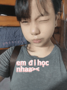 a girl with her eyes closed wearing a shirt that says em di hoc nhaa